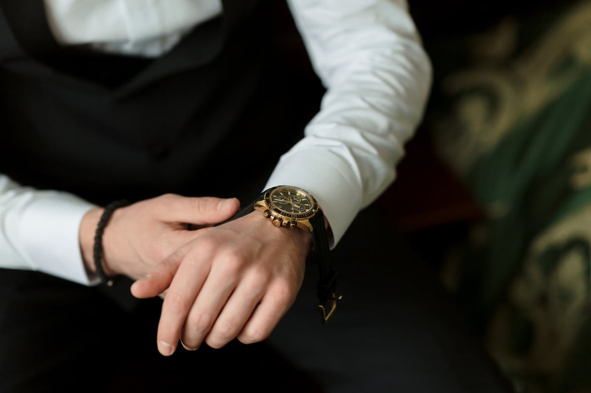 A man wearing a black suit and a gold watch
