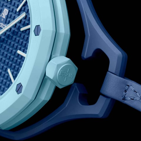 Close-up of a light blue and dark blue sports watch with hexagonal markers on the bezel against a black background